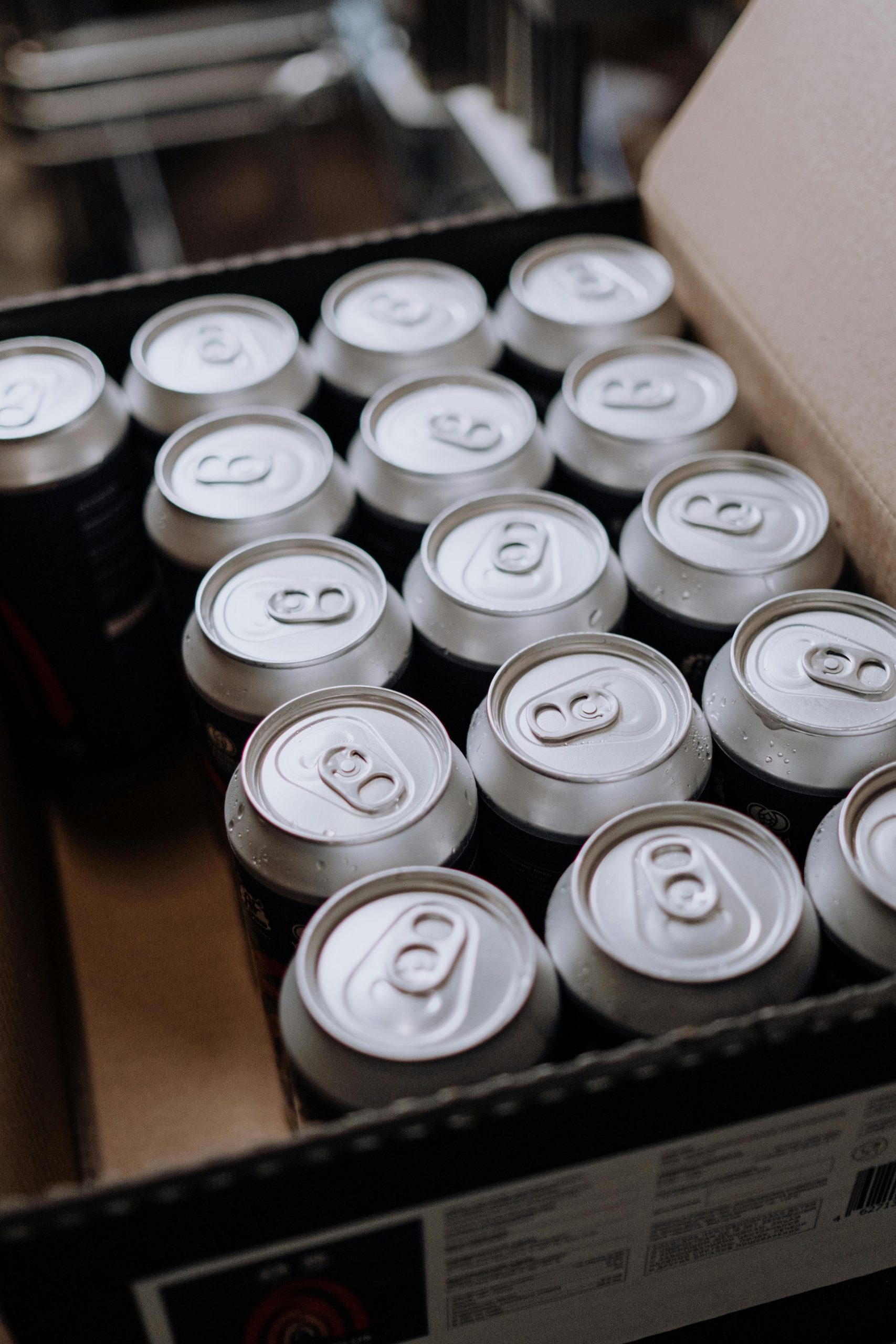 Close-up of aluminum drink cans packed neatly in a cardboard box, displayed from above.